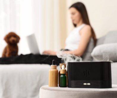 Aromatherapy diffuser with essential oils and a woman working on a laptop with a dog in the background, Aromatherapy diffuser with essential oil bottles on a side table, creating a relaxing atmosphere